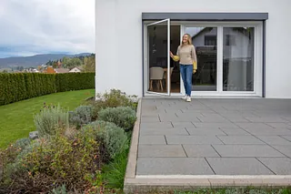 Eine Frau sitzt am Fenster mit Insektenschutz